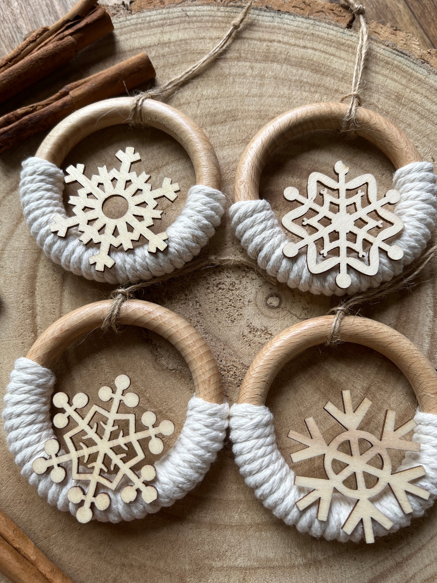 Four decorative wooden ornaments, made on wooden rings with natural yarn and finished with wooden snowflake designs.