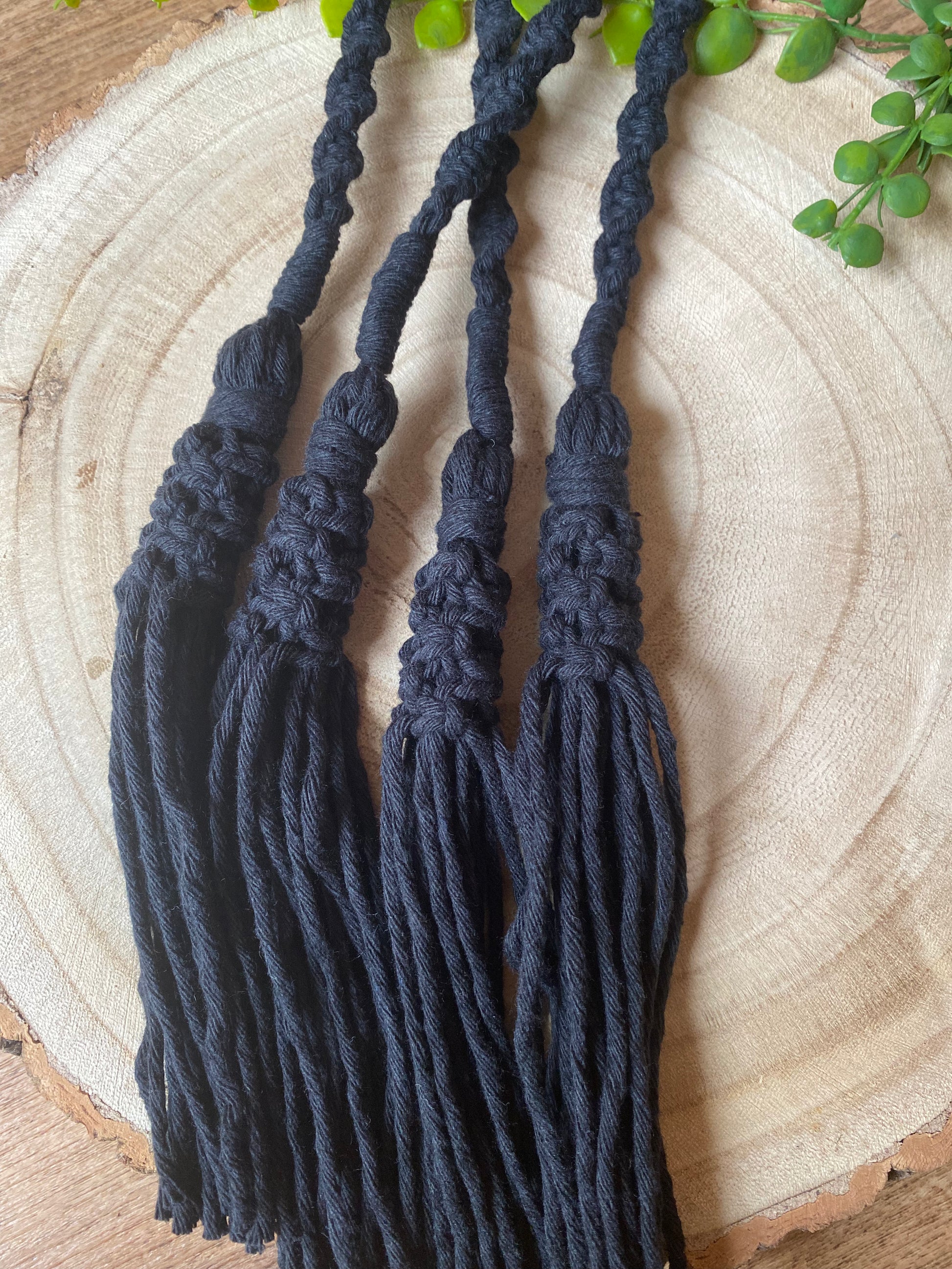 A pair of knotted macrame tassel tiebacks, made with black cotton yarn.