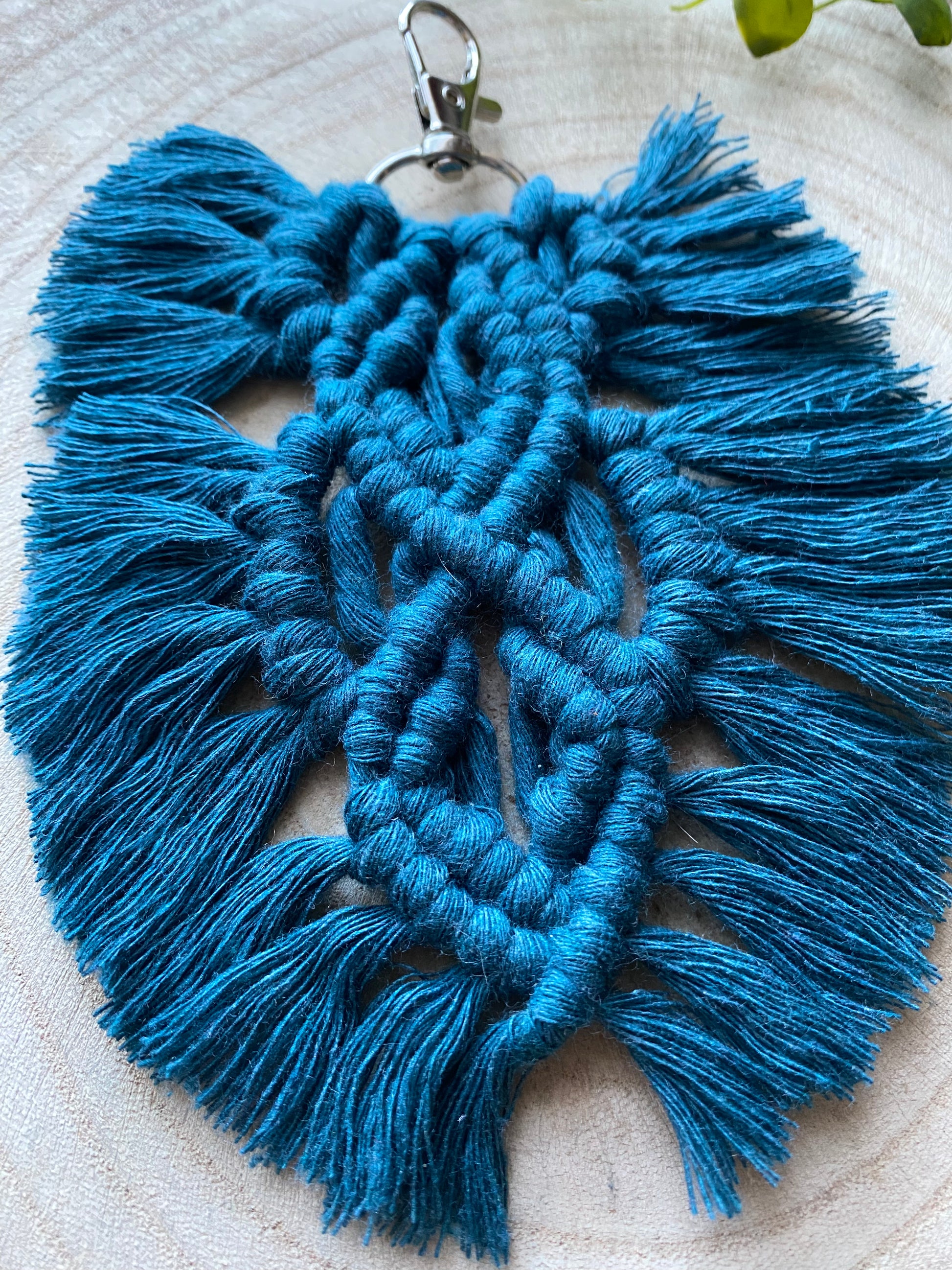 Handmade macrame feather shaped keyring, made with peacock blue recycled cotton and a small metal clasp.