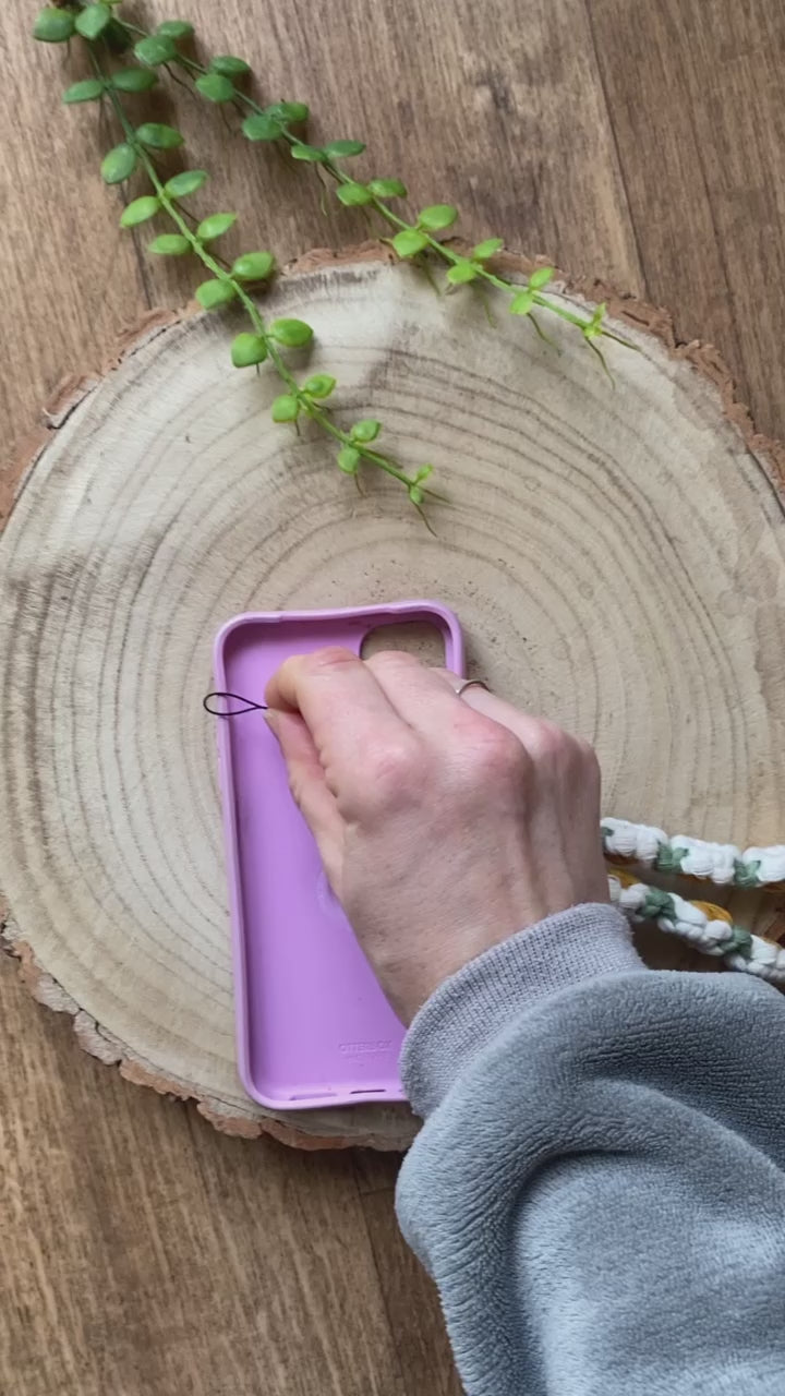 a video demonstrating how to attach macrame daisy chain phone charm wristlet to a phone case