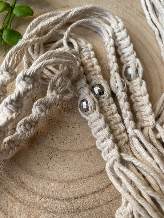 Close up of a handmade macramé plant hanger with recycled cotton cord, featuring small mirror disco ball beads woven into the design.