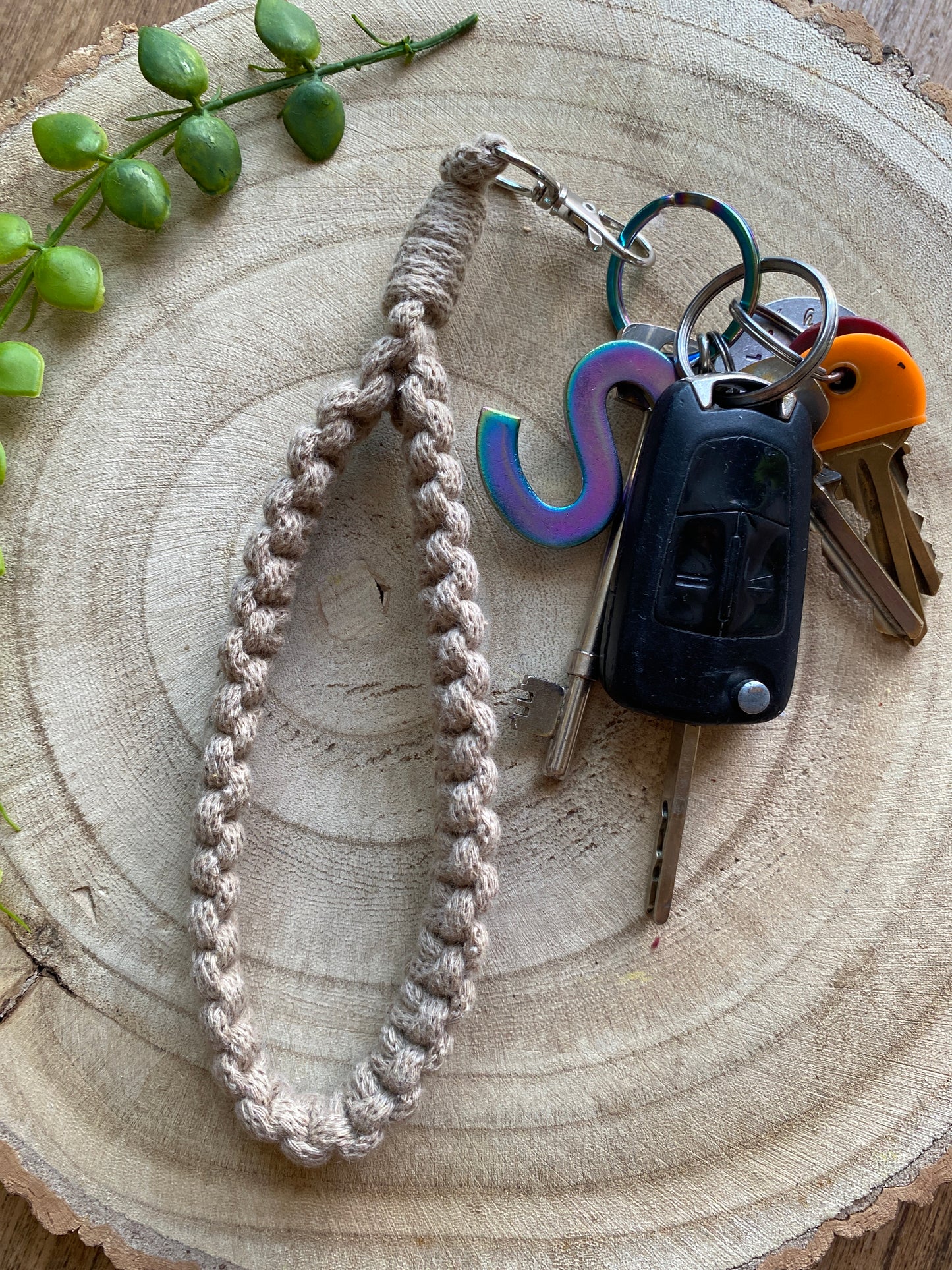 Handmade macrame wristlet keychain with metal clasp, made with beige recycled cotton. Shown attached to a small set of car keys.