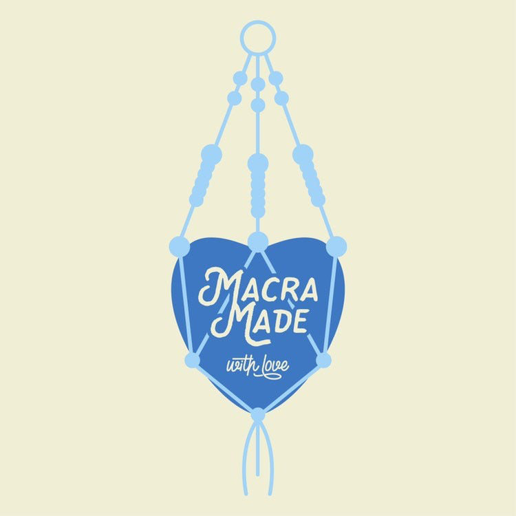 An illustration of a DIY macrame wall hanging featuring a heart-shaped centerpiece in blue, adorned with the words "Macra-Made-With-Love" in stylized white lettering. The intricately designed macrame piece includes beads and knots, showcasing a handcrafted aesthetic that is perfect for Christmas craft kits. This piece is part of the Macrame Christmas Tree tutorial - PDF pattern + video collection by Macra-Made-With-Love.