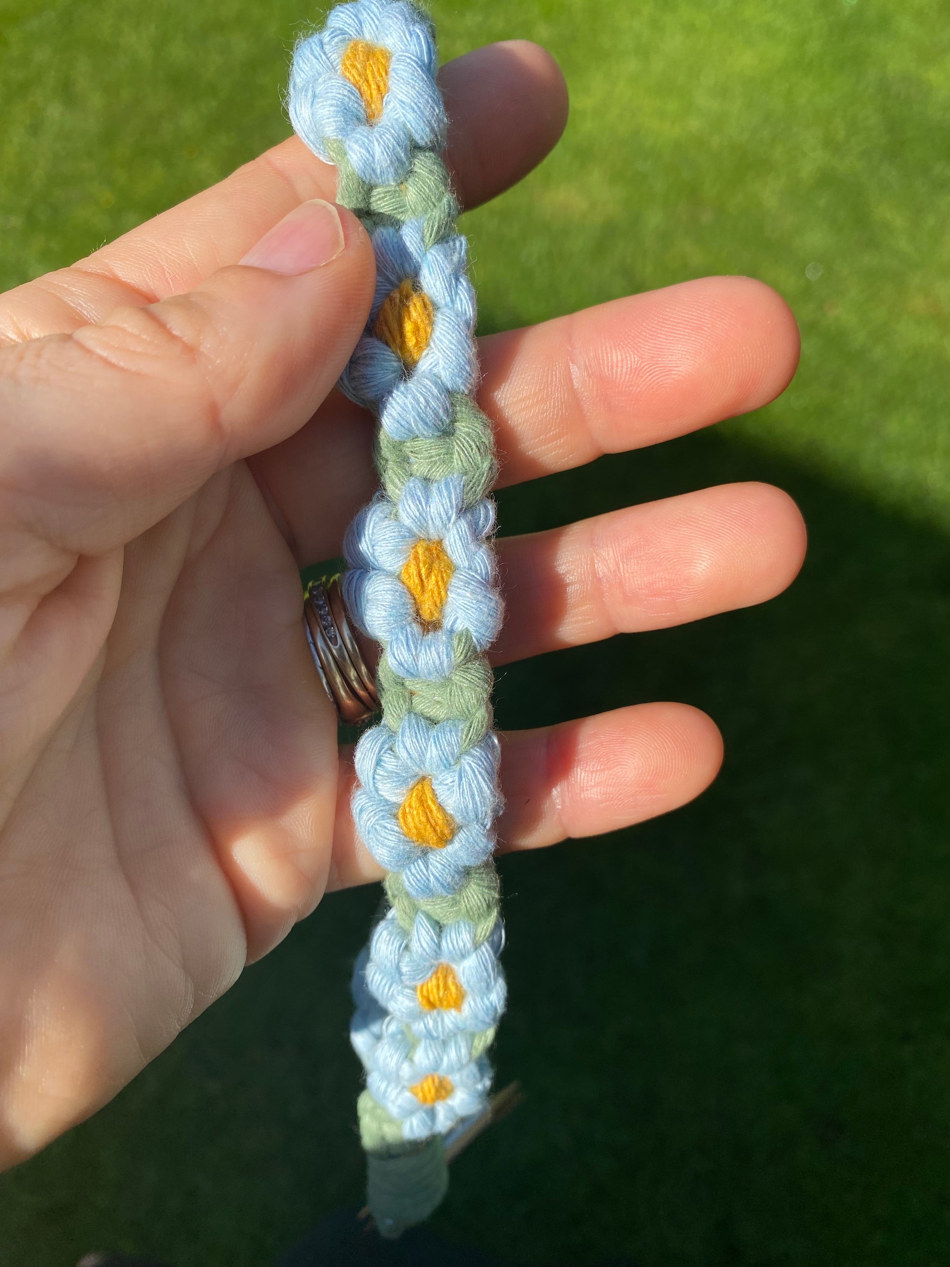 Macra-Made With Love daisy chain phone wrist strap blue in hand outside