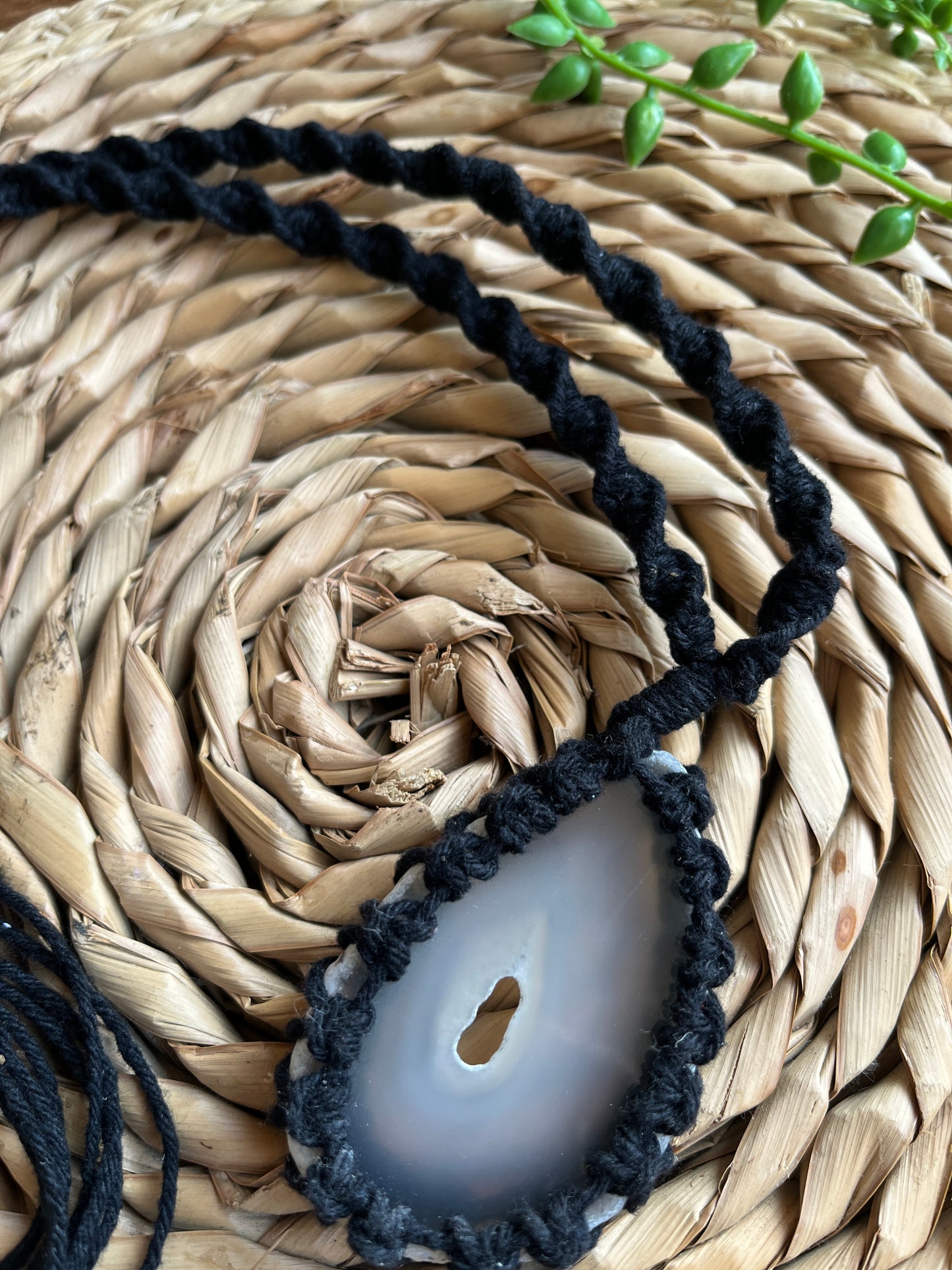 Close up of natural agate slice in black macrame necklace 