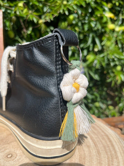 Handmade macrame daisy boot charm, made with recycled cotton, attached to a pair of black hi top boots with a metal split ring