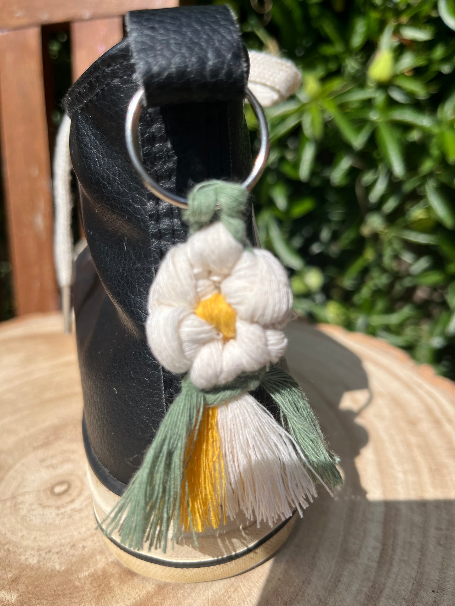 Handmade macrame daisy boot charm, made with recycled cotton, attached to a pair of black hi top boots with a metal split ring