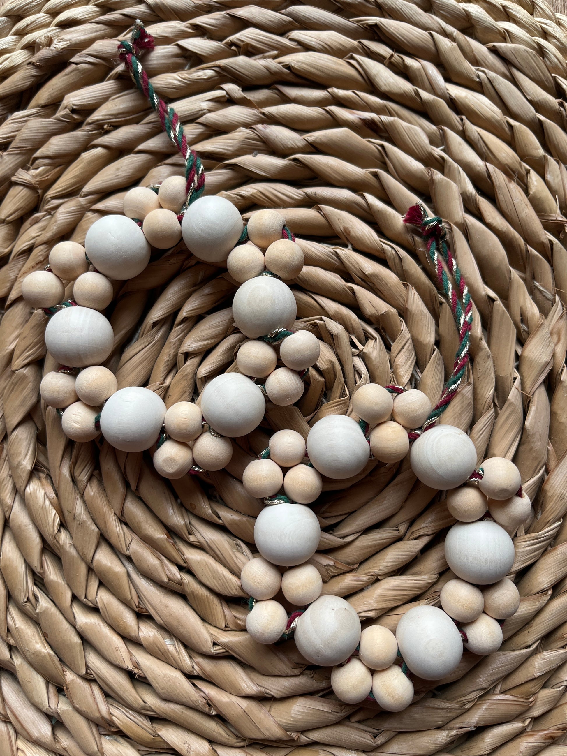 Two wooden bead garlands on a woven mat