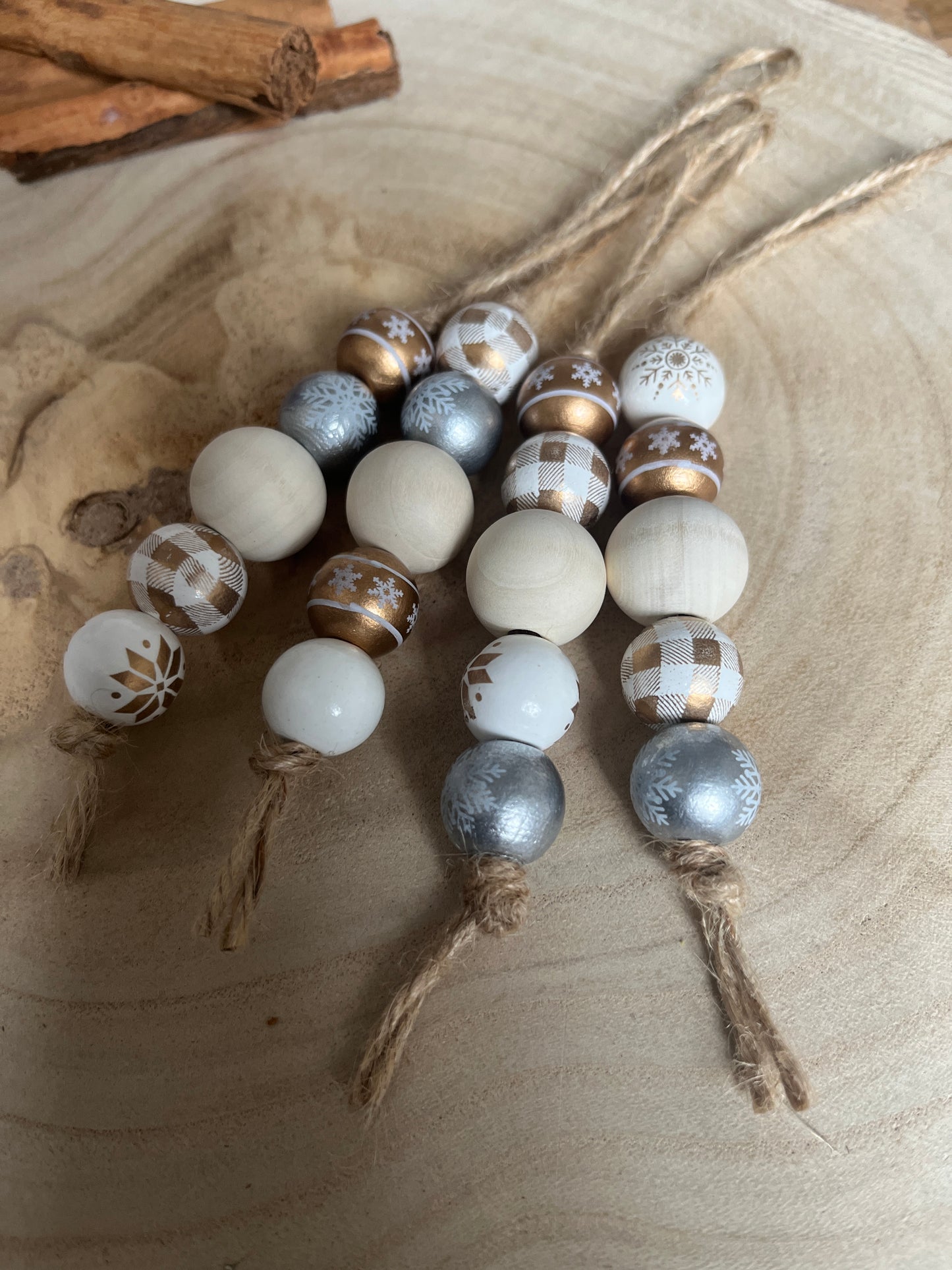 Decorative string of beads with white, gold, and silver tones on a wooden surface.