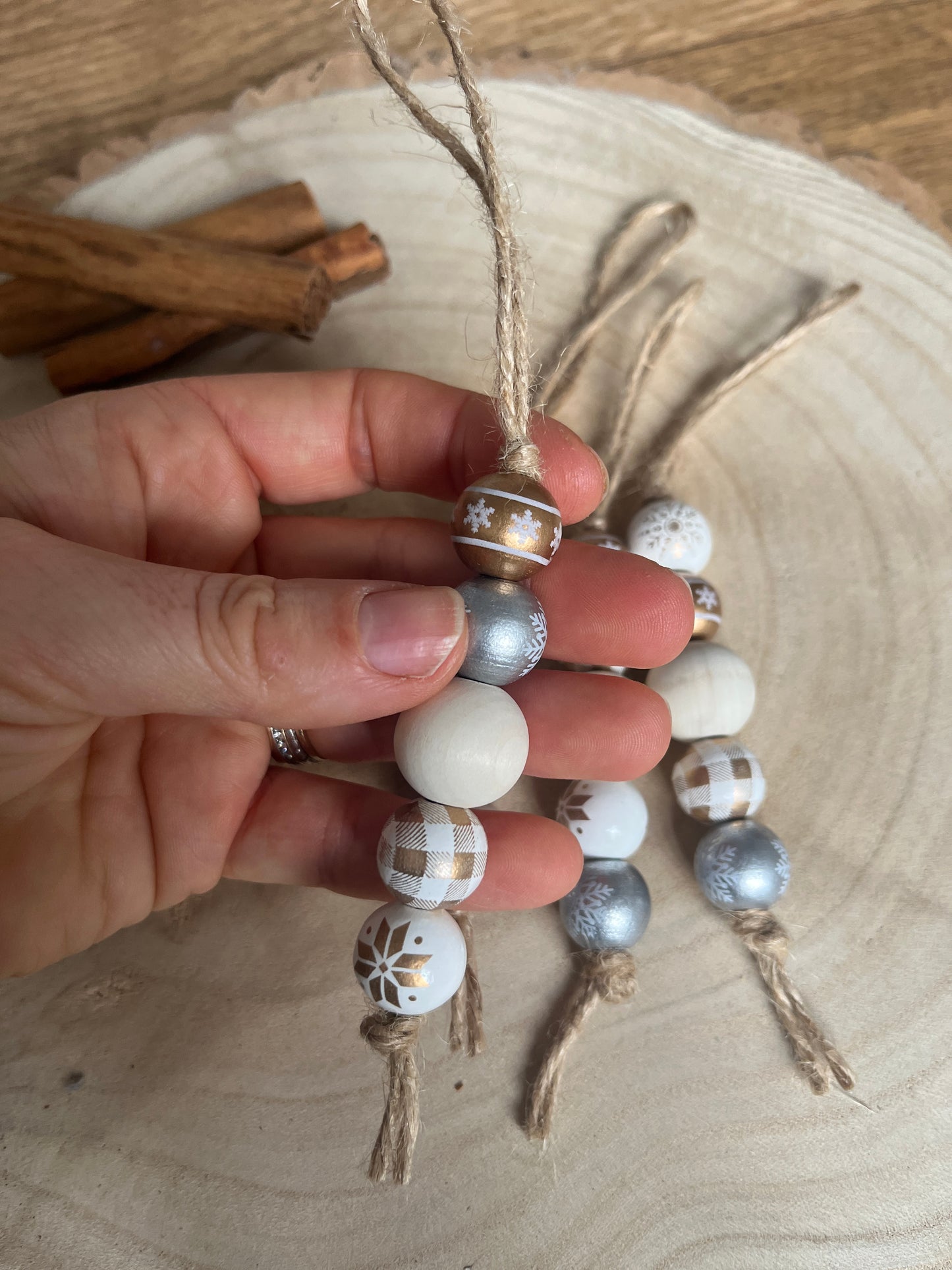 Hand holding a decorative bead ornament with a wooden background