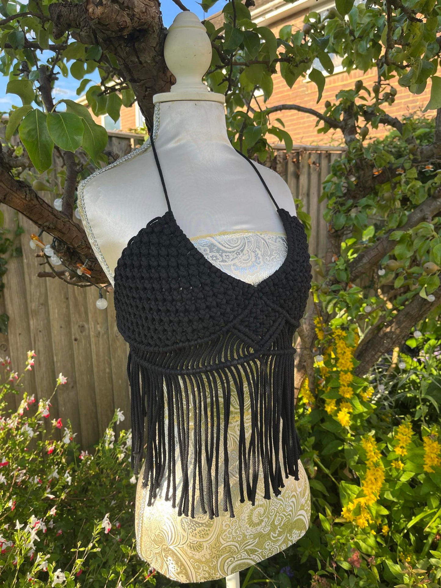 Black fringe top on a mannequin against a garden background