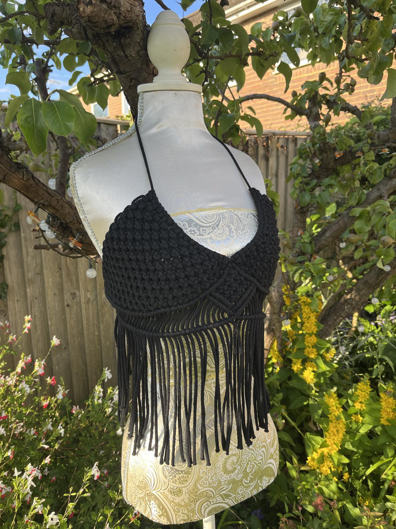Black fringe top on a mannequin against a garden background