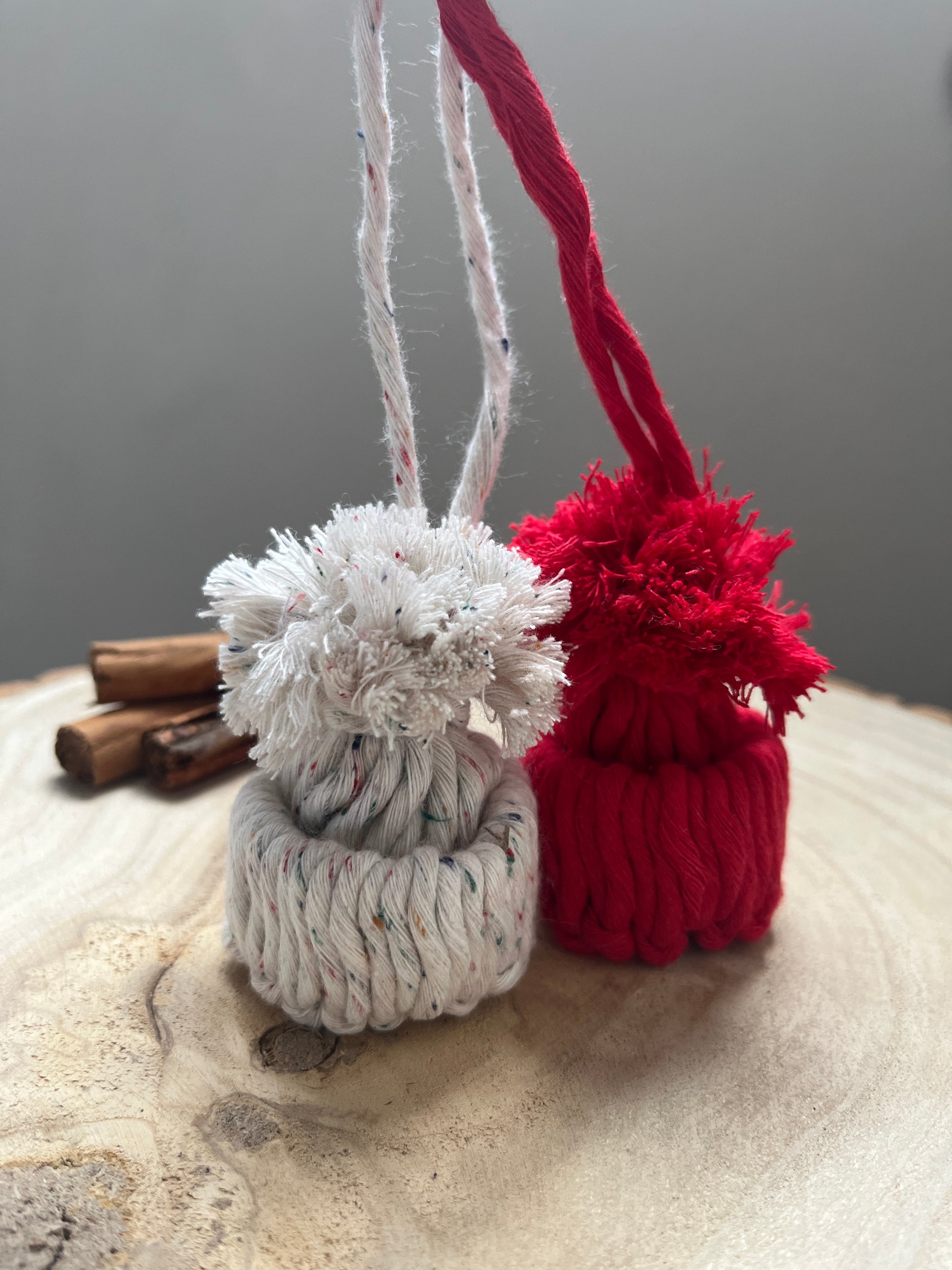 Decorative bobble hat ornaments made with red and white yarn on a wooden surface.