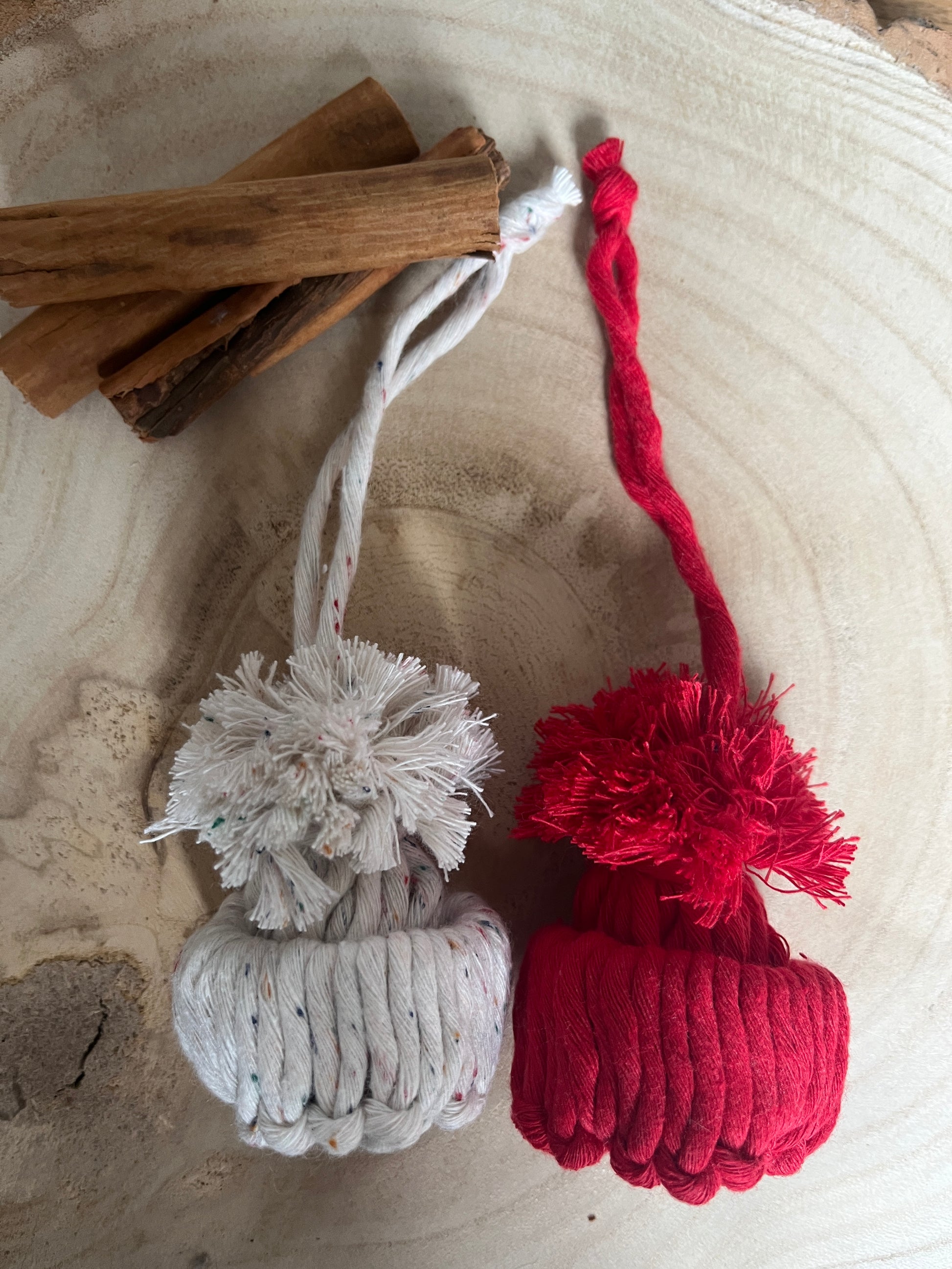 Red and white pom-pom ornaments with cinnamon sticks on a textured surface