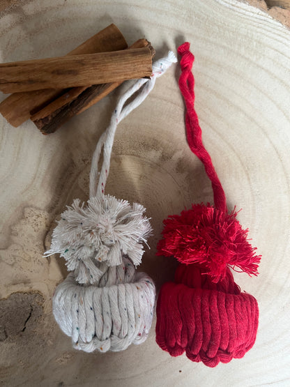 Red and white pom-pom ornaments with cinnamon sticks on a textured surface