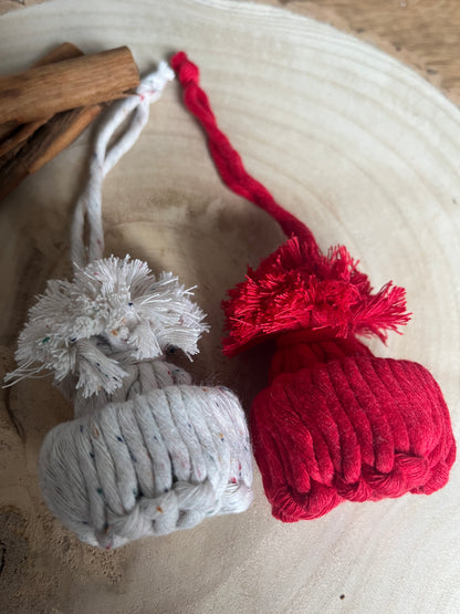 Red and white yarn pom pom hat decorations with tassels on a textured surface