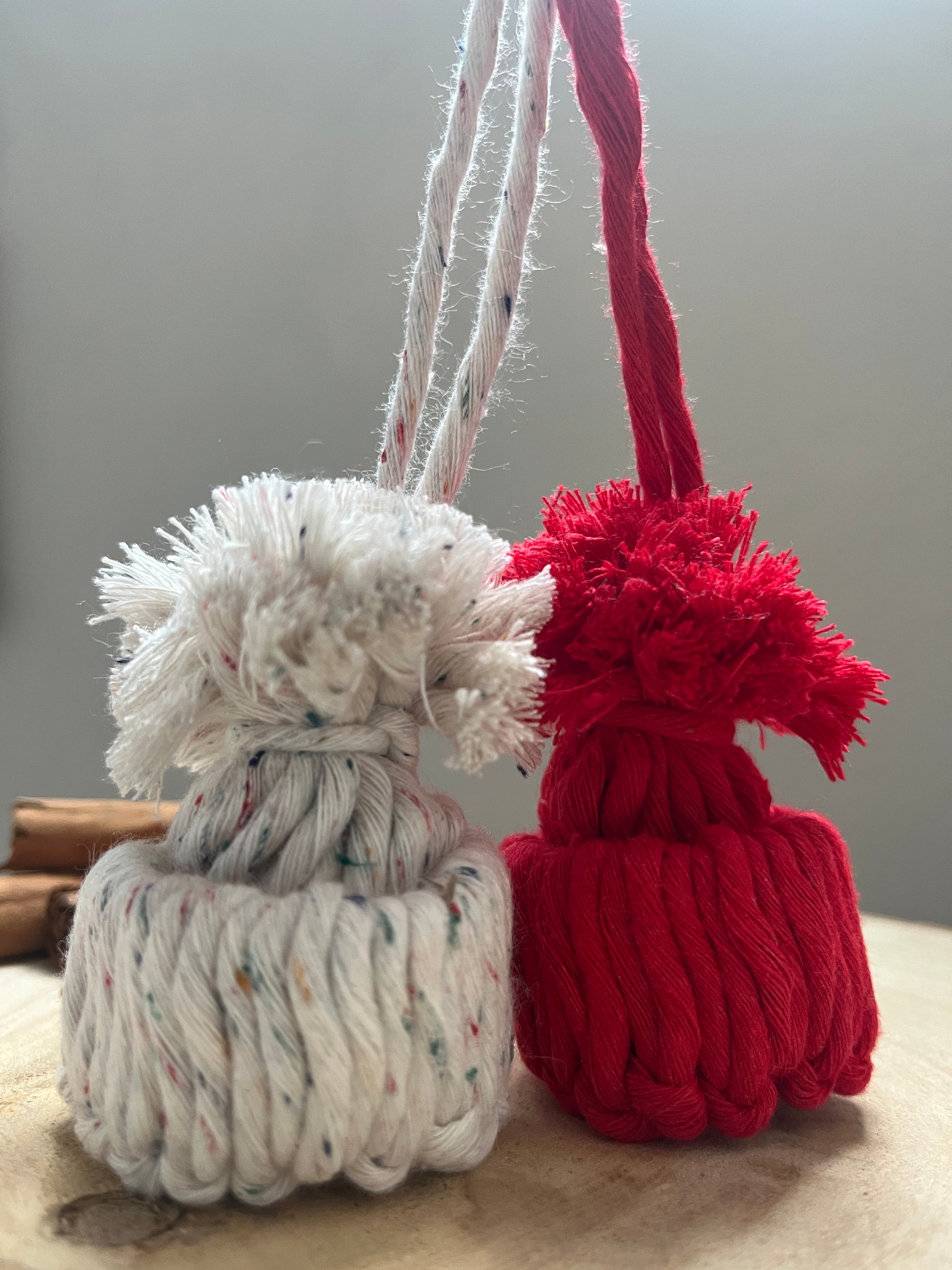 Close-up of red and white pom-pom hat ornaments against a plain background
