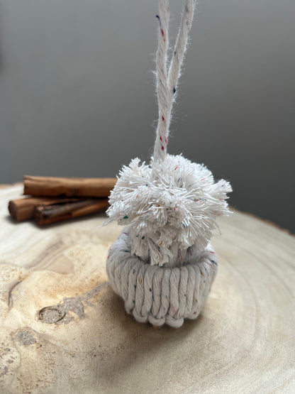 Close-up of a mini pom pom hat ornament on a wooden board. 
