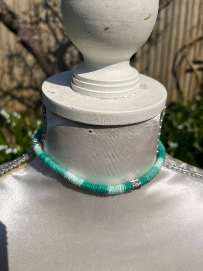 Handmade macrame surfer style short boho necklace, handmade using eco friendly green variegated yarn, and 3 Celtic style spacer beads. Displayed on a white mannequin, outside in the sunshine. 