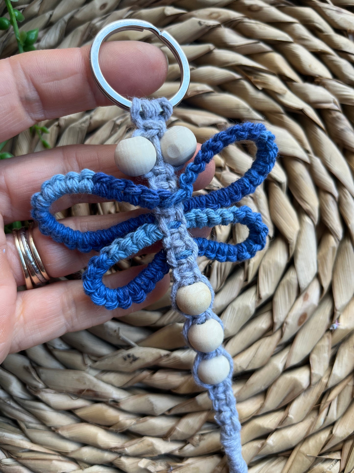 Handmade macrame dragonfly keyring or bag charm, made using shades of blue recycled cotton, on a metal split ring, with small wooden beads. 