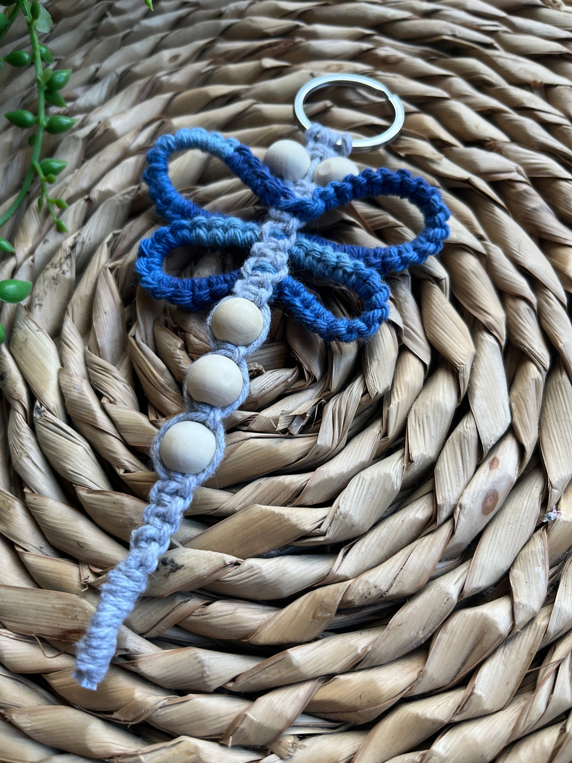 Handmade macrame dragonfly keyring or bag charm, made using shades of blue recycled cotton, on a metal split ring, with small wooden beads. 
