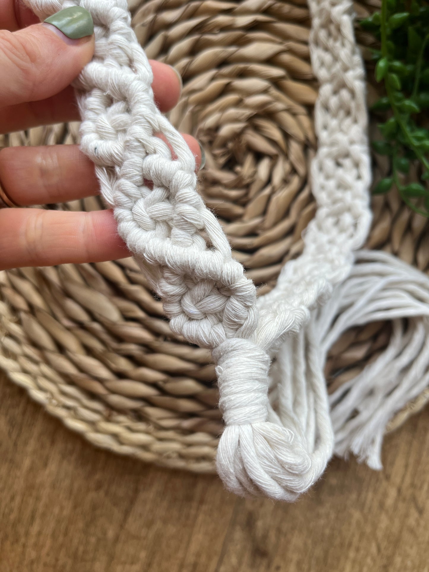 A handmade boho style macrame hat band featuring an intricate knot pattern. 