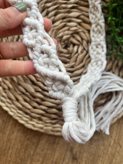 A handmade boho style macrame hat band featuring an intricate knot pattern. 