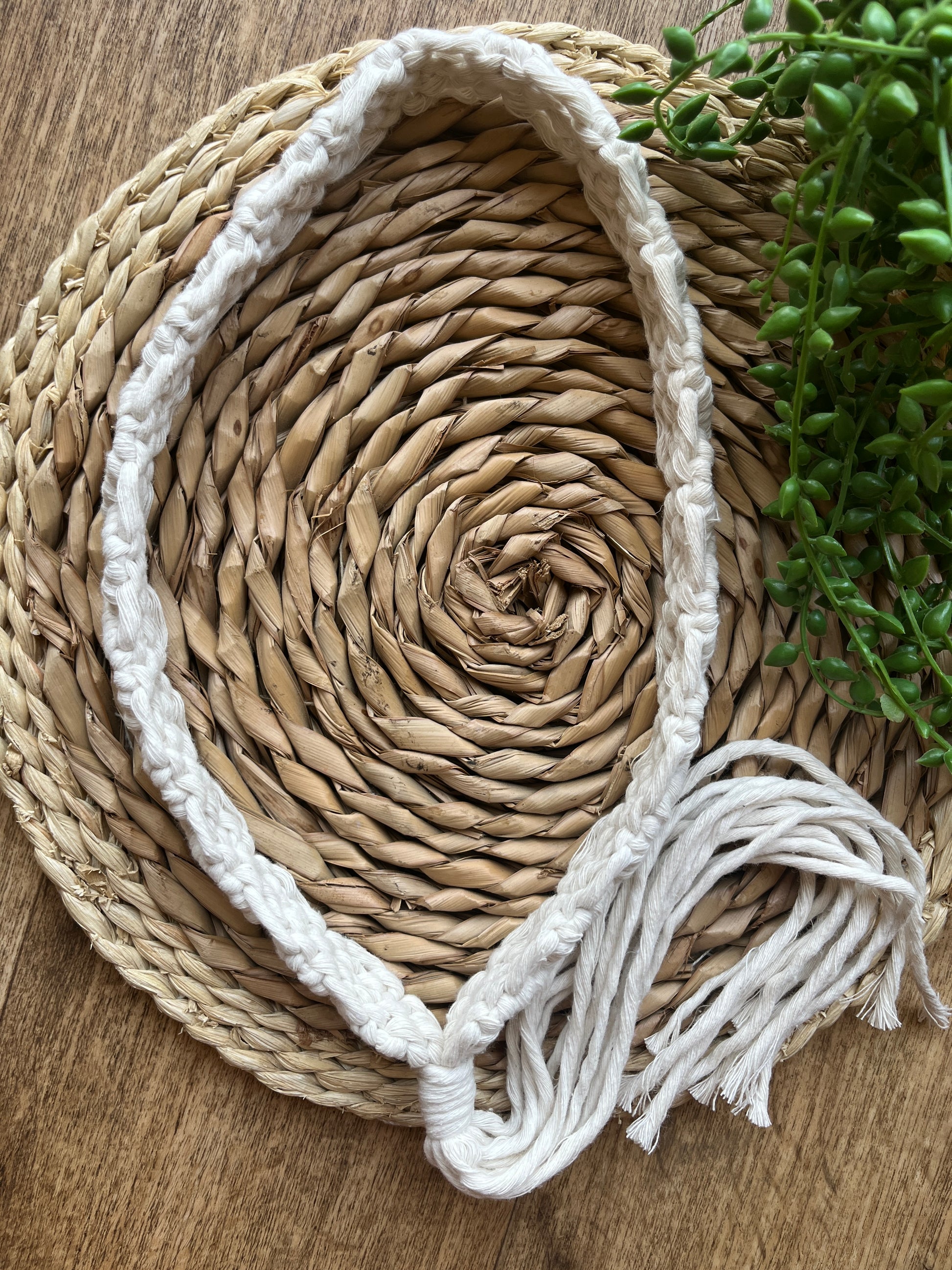 A handmade boho style macrame hat band with a long tassel, made with recycled cotton, and an intricate knot pattern. 