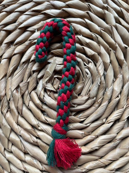 Braided red and green candy cane decoration on a woven surface