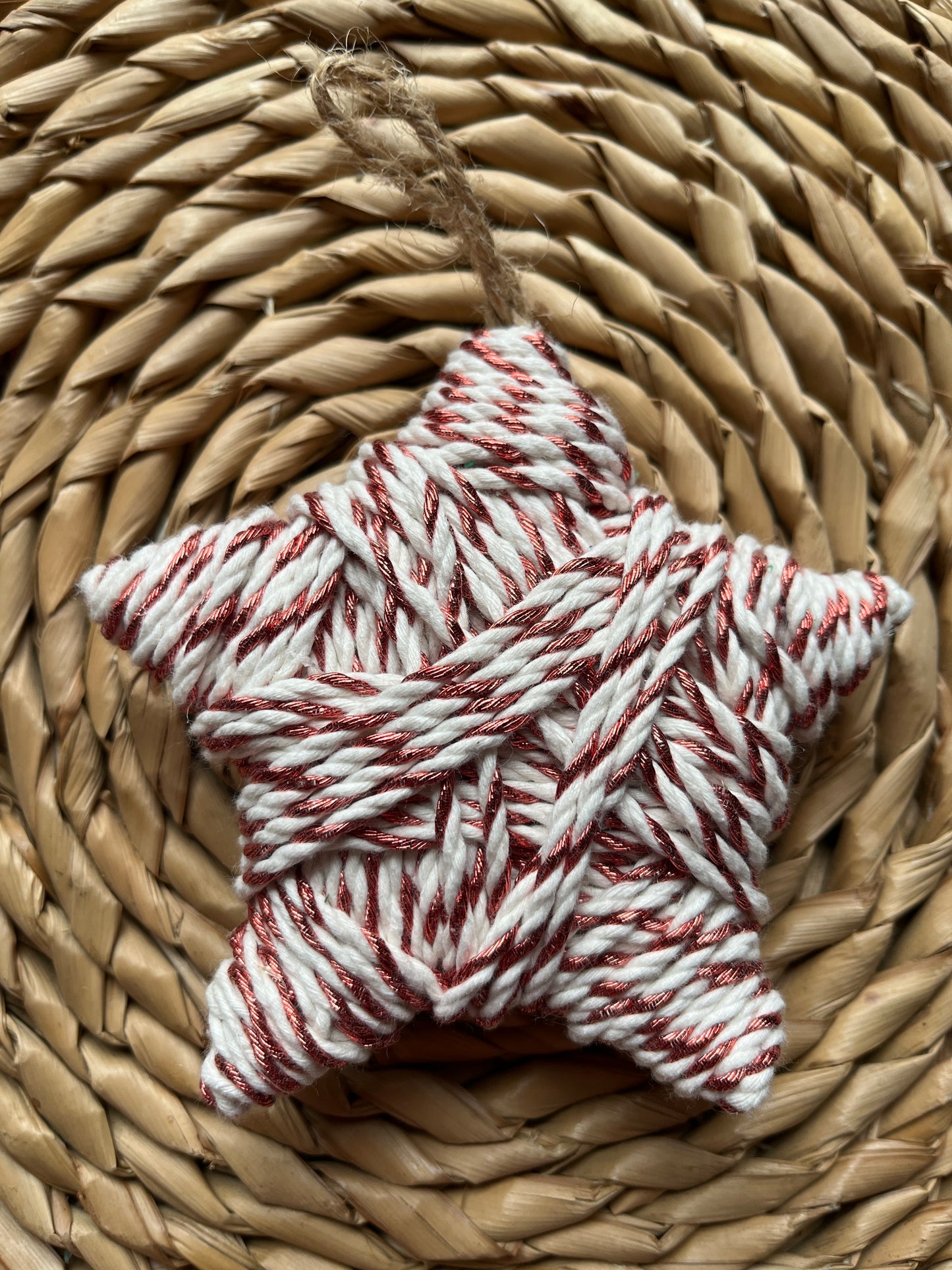 Star-shaped decoration made of copper and white yarn on a woven surface