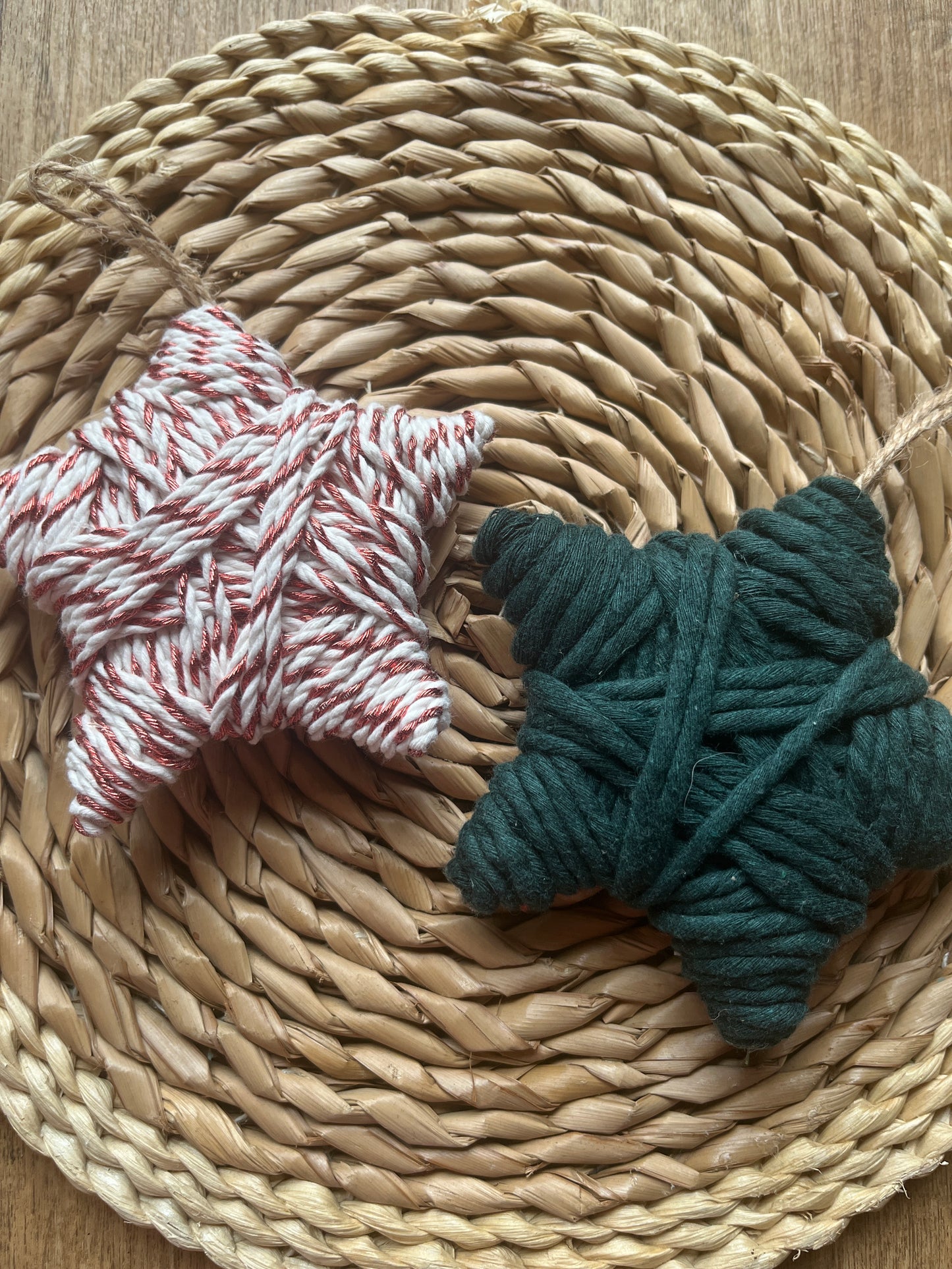 Two woven star decorations made with yarn, on a woven surface 