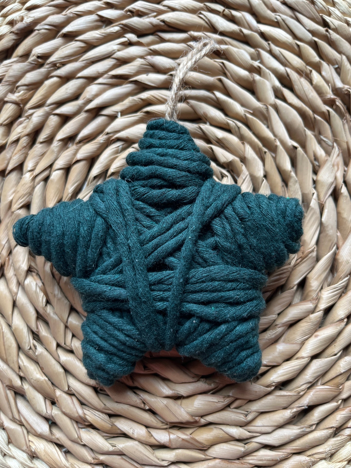 Star decoration made with dark green yarn, on a woven surface 