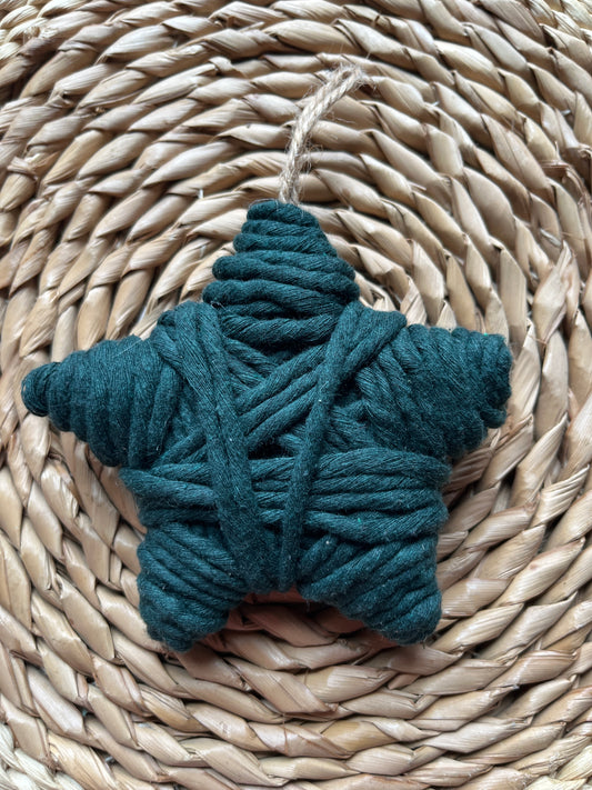 Star decoration made with dark green yarn, on a woven surface 