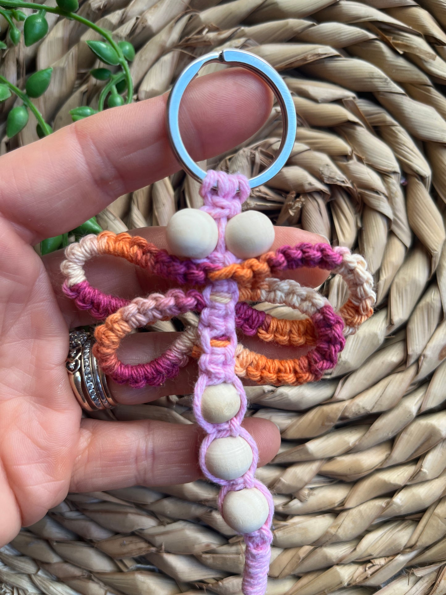 Handmade macrame dragonfly keyring or bag charm, made using shades of pink recycled cotton, on a metal split ring, with small wooden beads. 