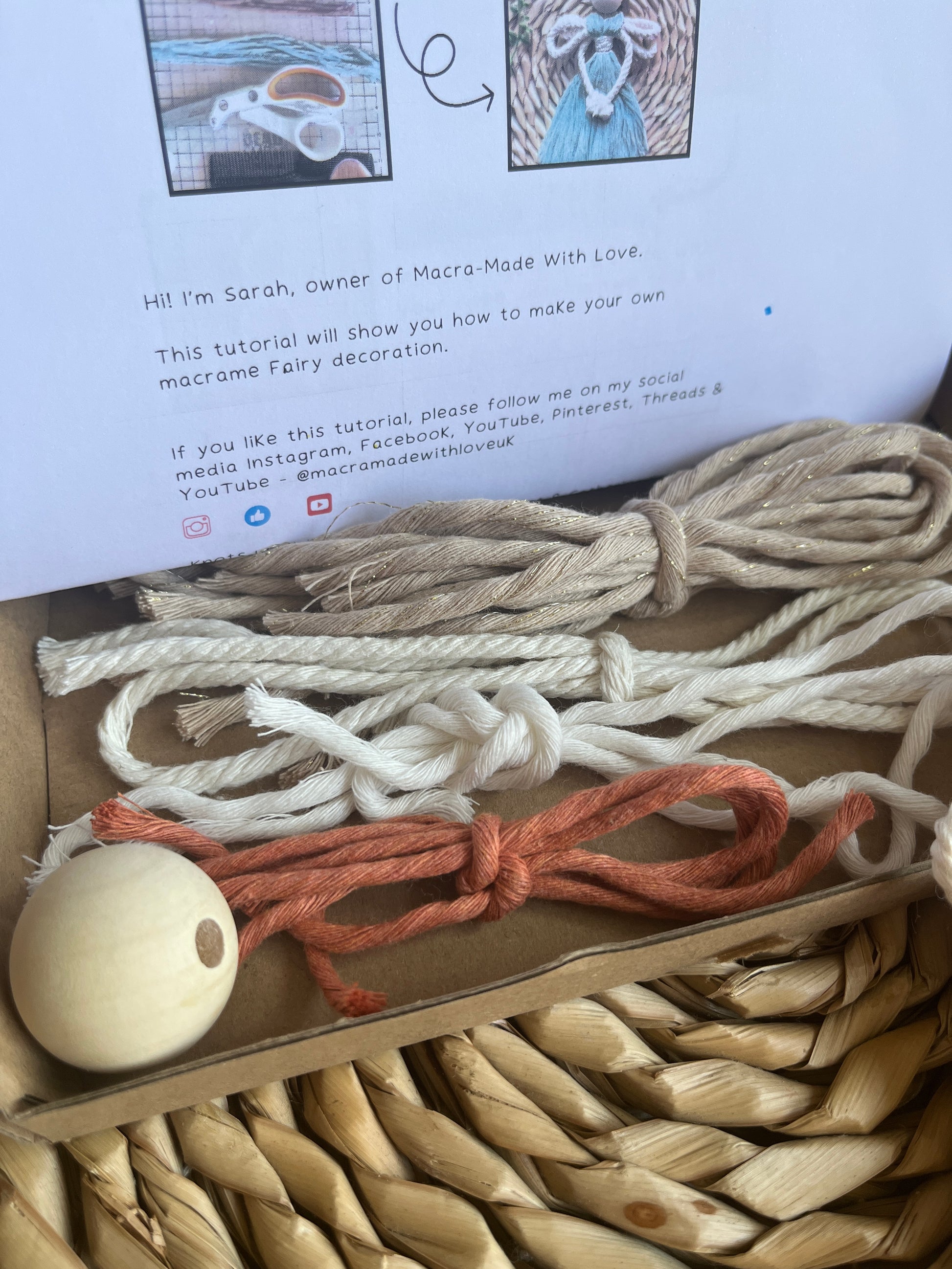 Pre cut yarn and a wooden bead on an open box with printed instructions for a craft kit in the background. 