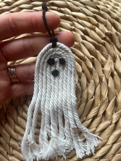 White tassel ghost held by a hand against a woven mat background