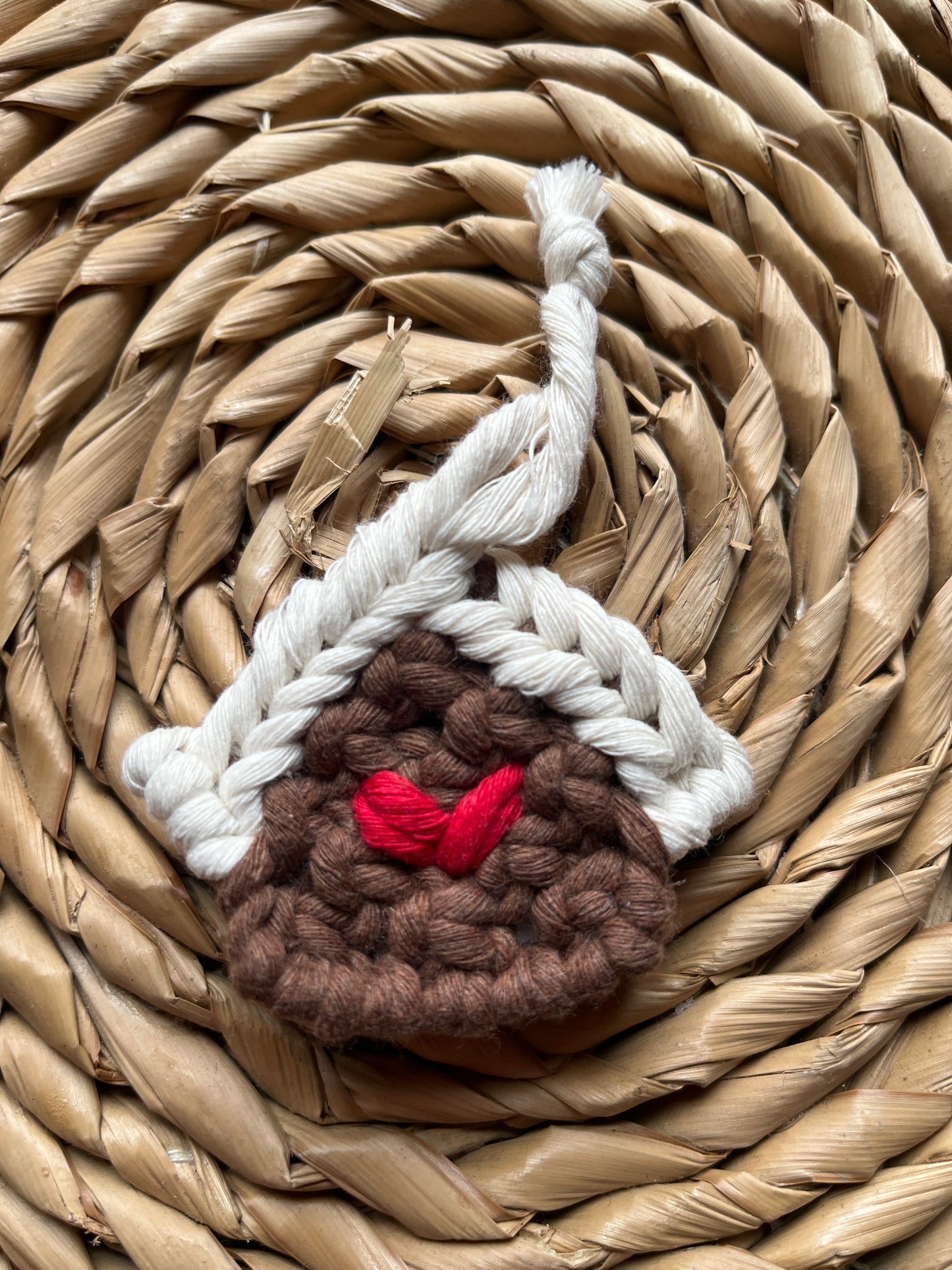 Brown knotted gingerbread house decoration placed on a woven mat.