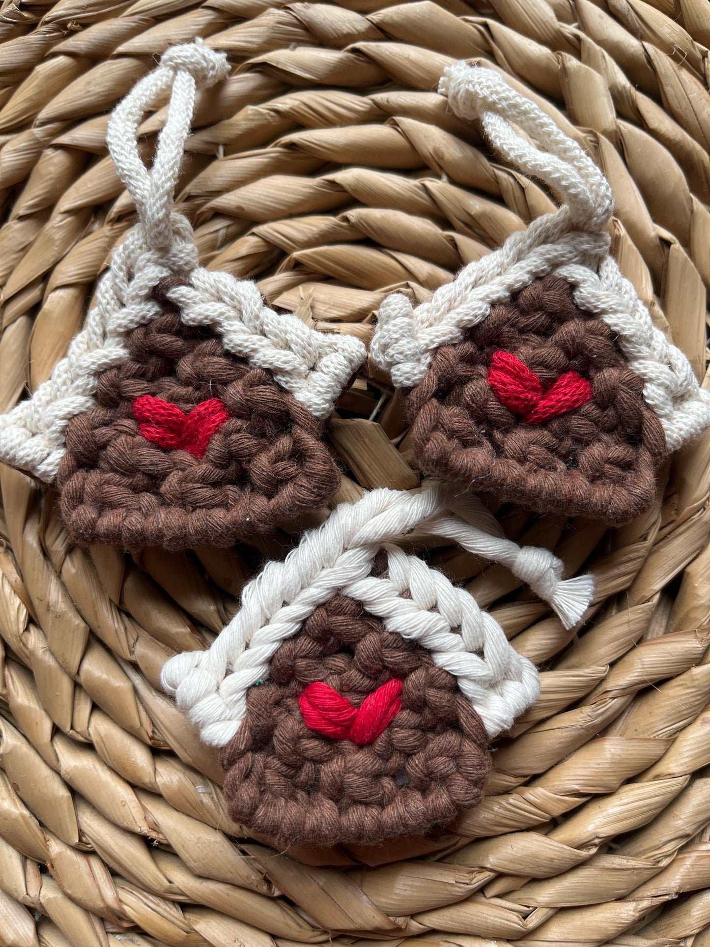 Three handmade macrame gingerbread house decorations on a woven surface