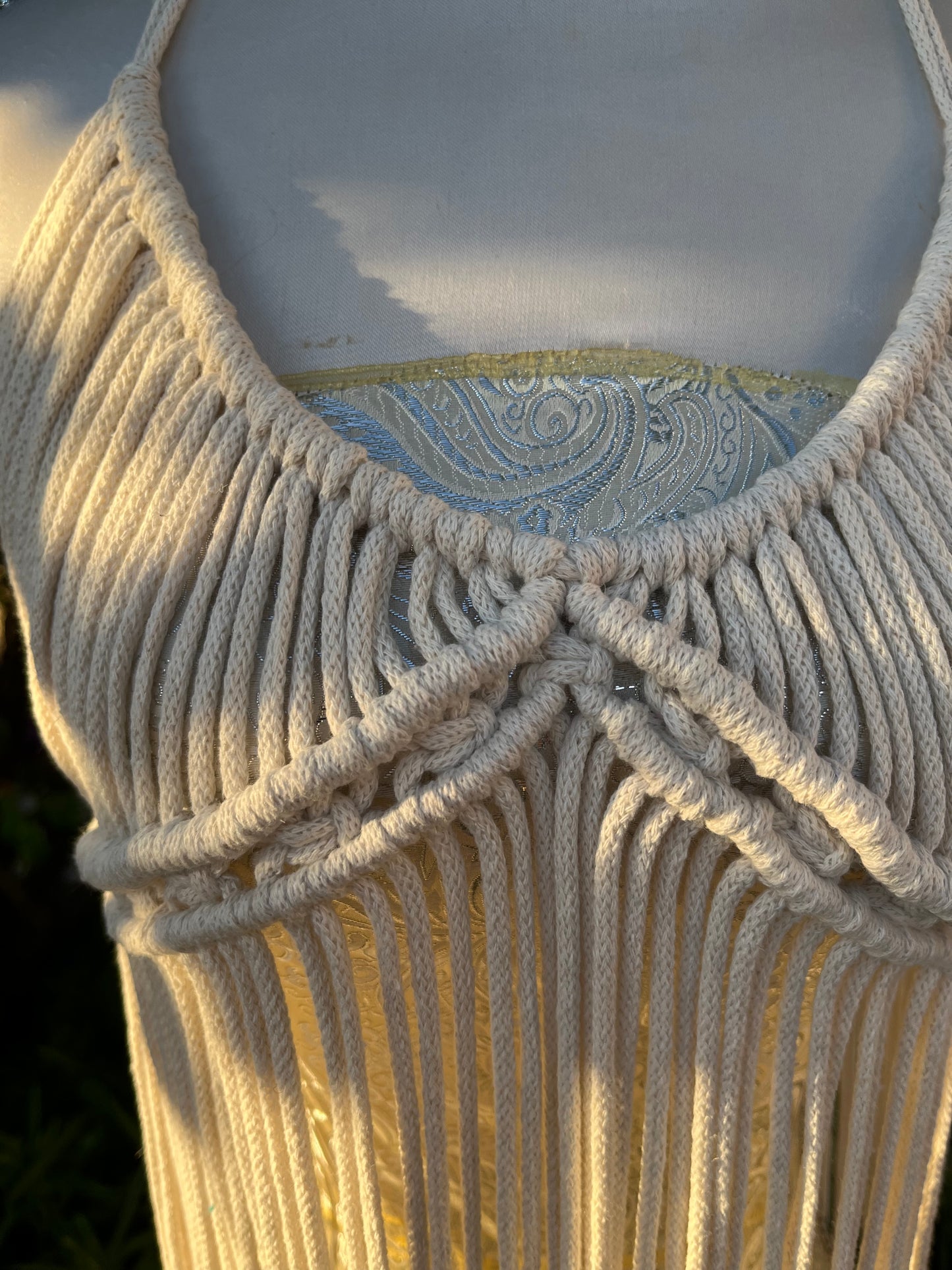 Close up of the neckline on a a natural macrame boho goddess dress coverup with displayed on a mannequin outdoors.