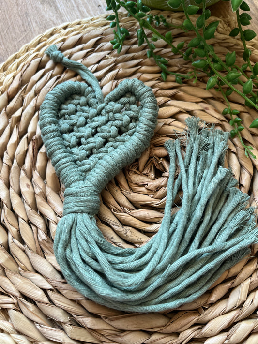 Close up of a macrame heart shaped decoration on a woven mat 