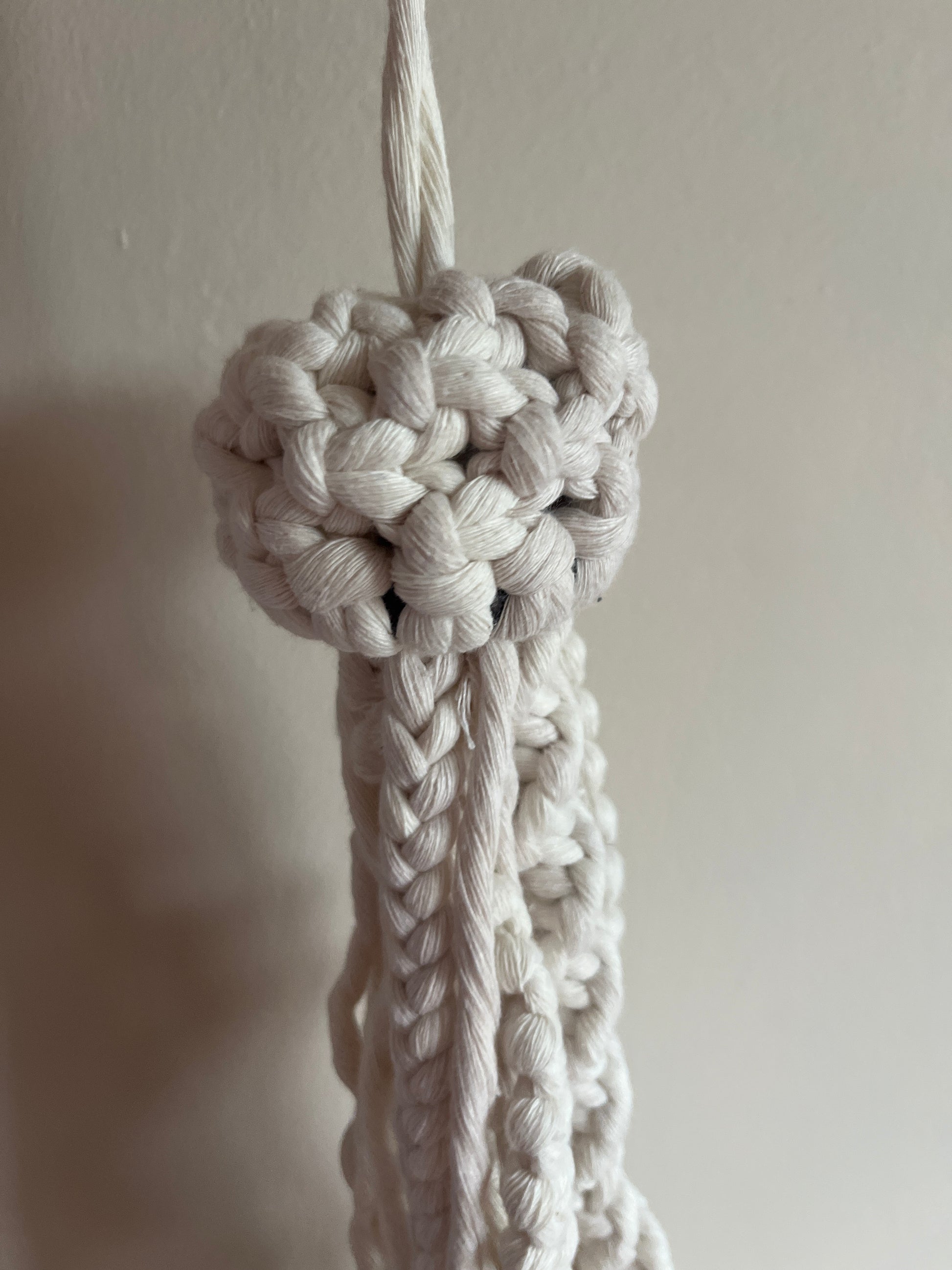 Close-up of a knotted macrame jellyfish on a plain background