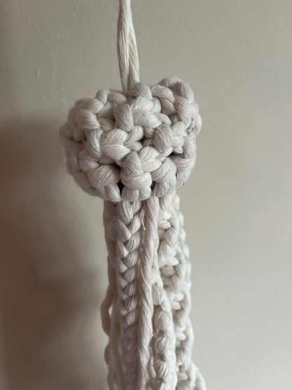 Close-up of a knotted macrame jellyfish on a plain background