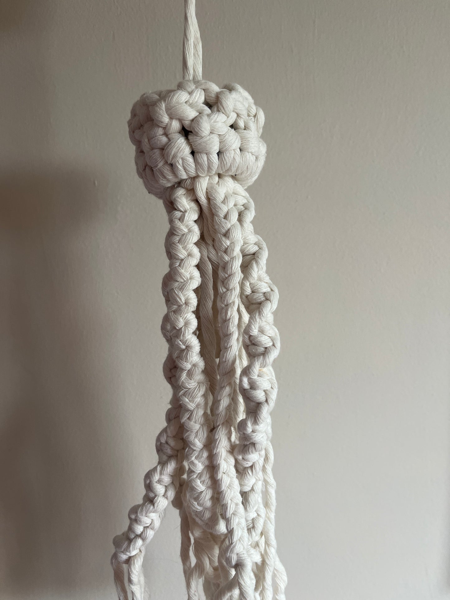 Close-up of a knotted white macrame jellyfish on a plain background