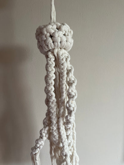 Close-up of a knotted white macrame jellyfish on a plain background