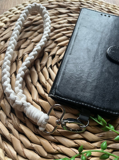 Close up of a black leather phone case, with a macrame phone wristlet attached