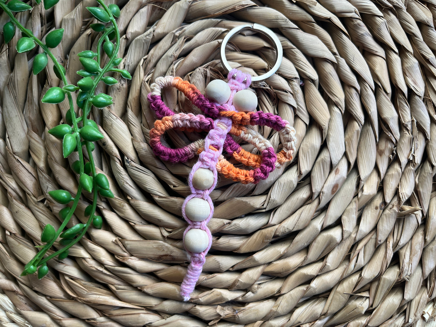 Handmade macrame dragonfly keyring or bag charm, made using shades of pink recycled cotton, on a metal split ring, with small wooden beads. 