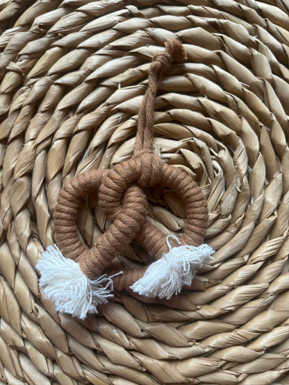 Brown rope pretzel ornament on a woven surface