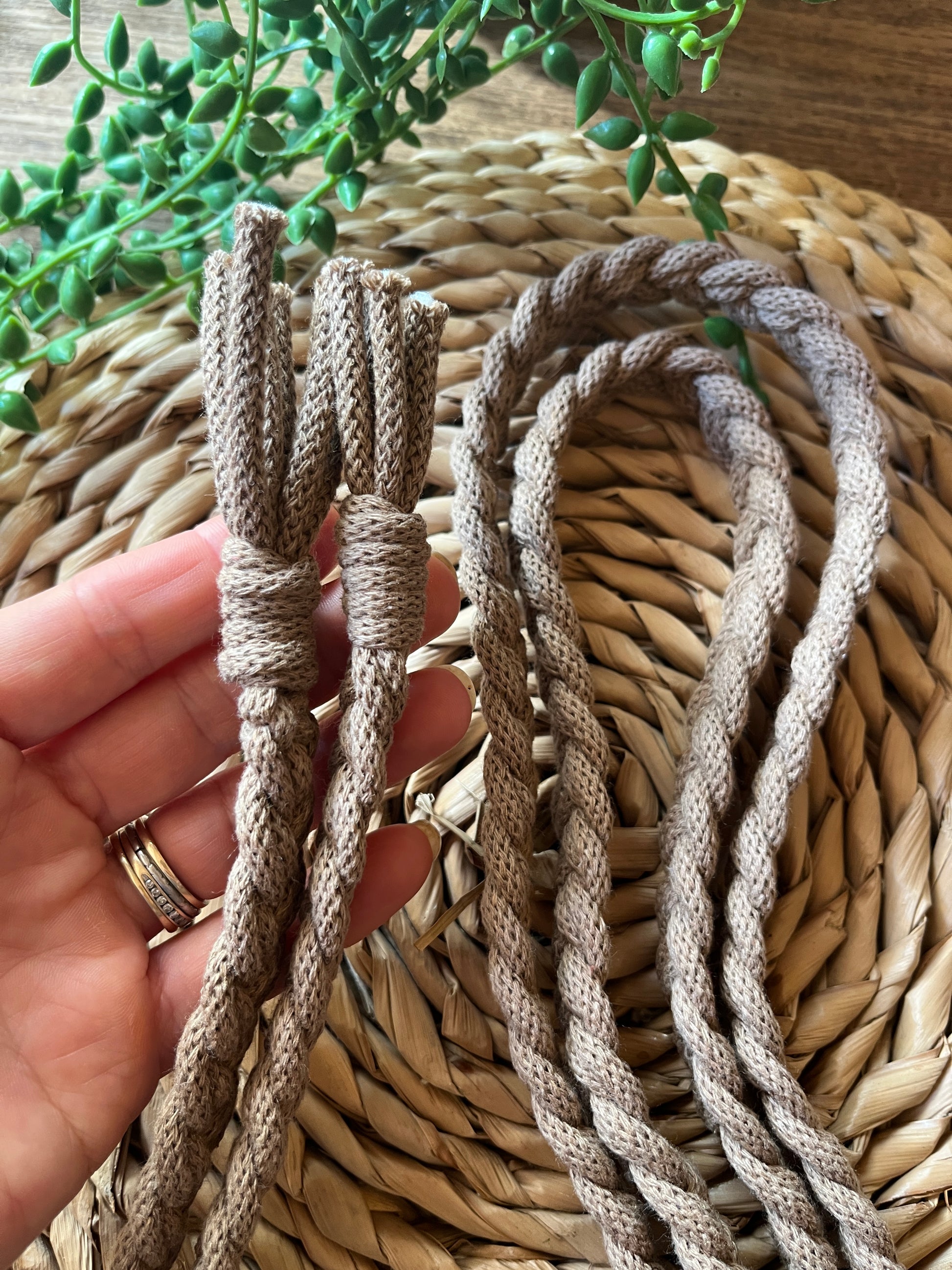 Close-up of braided rope held in a hand with a woven mat background.