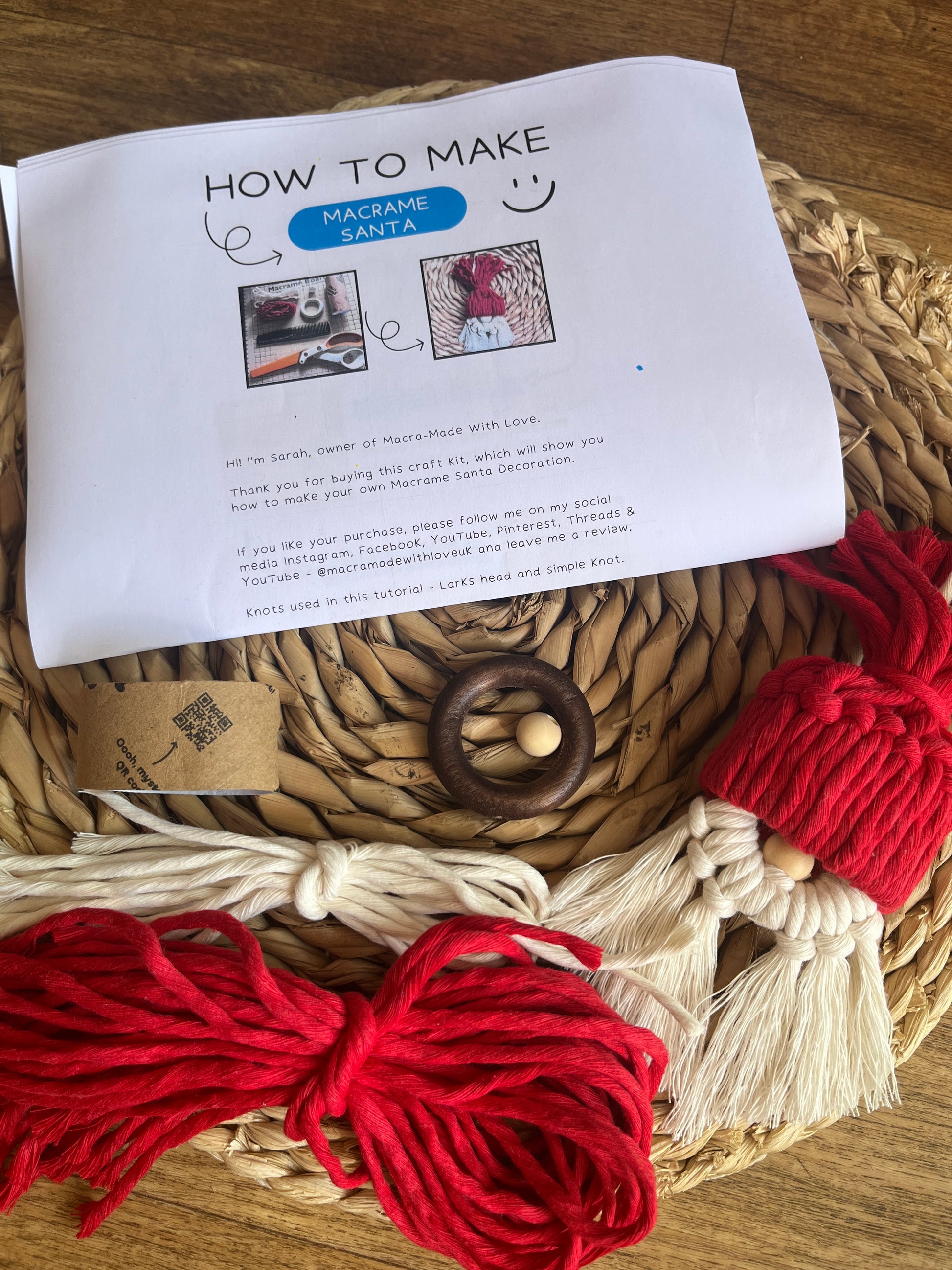 Macrame kit with red and white yarn and an instruction sheet on a woven mat.