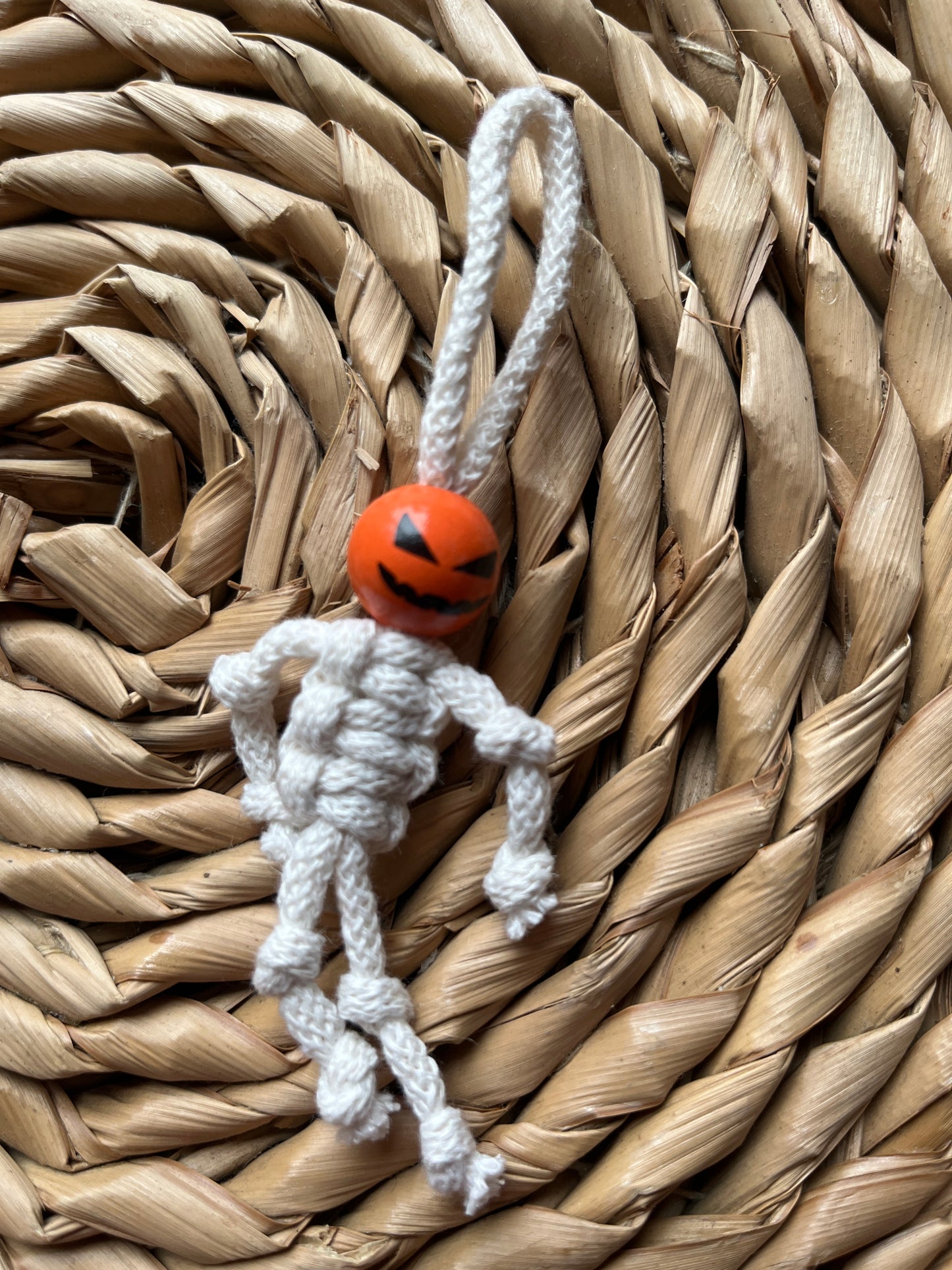 Macrame skeleton decoration made with natural yarn and an orange bead 